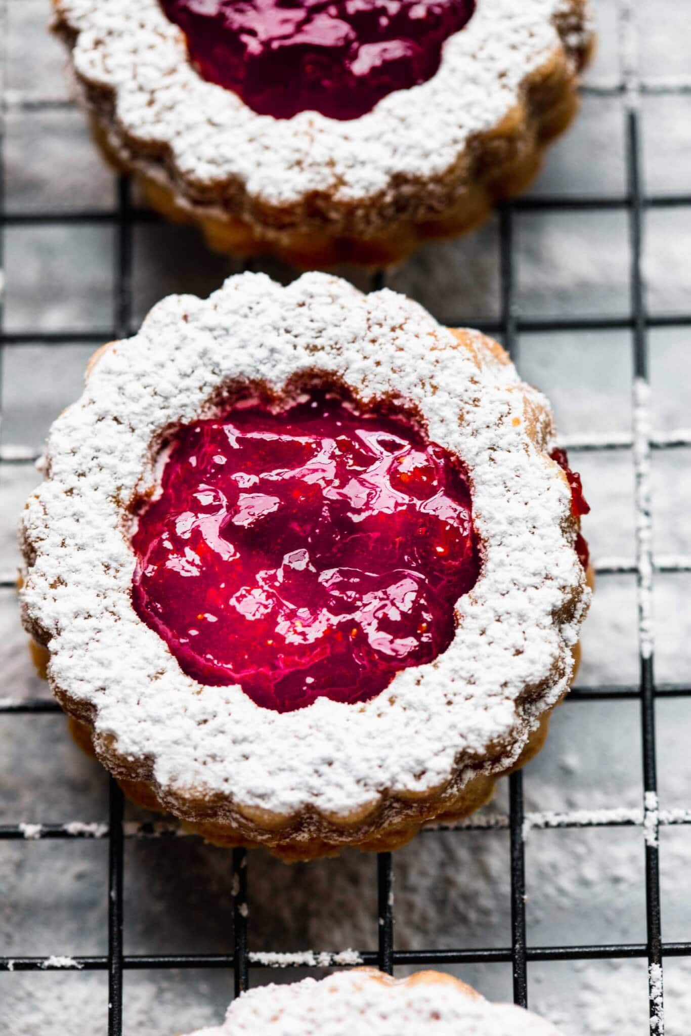 Overhead close up of linzer cookie dusted with powdered sugar and filled with strawberry jam.