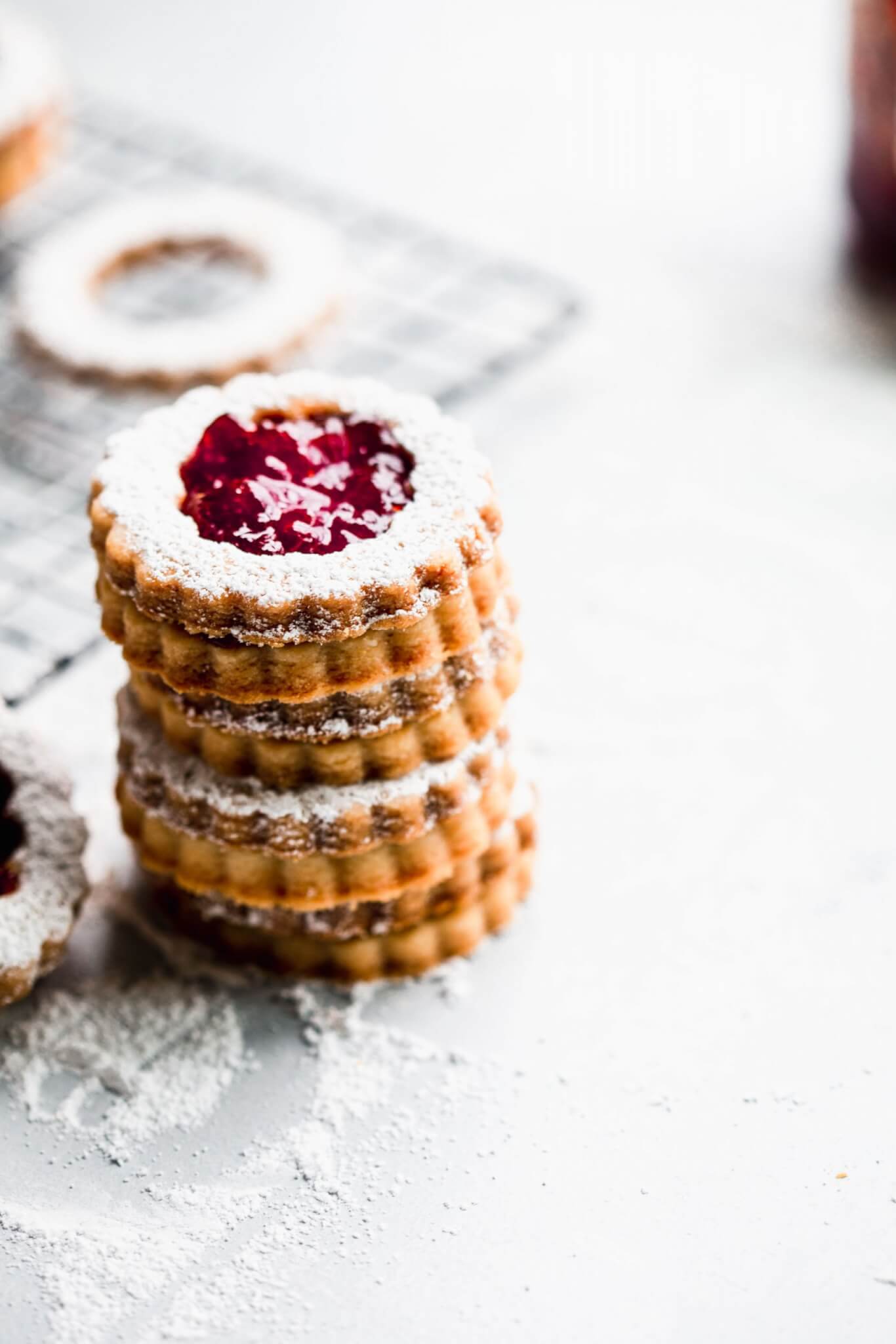 Side view of stack of linzer cookies next to cooling rack.