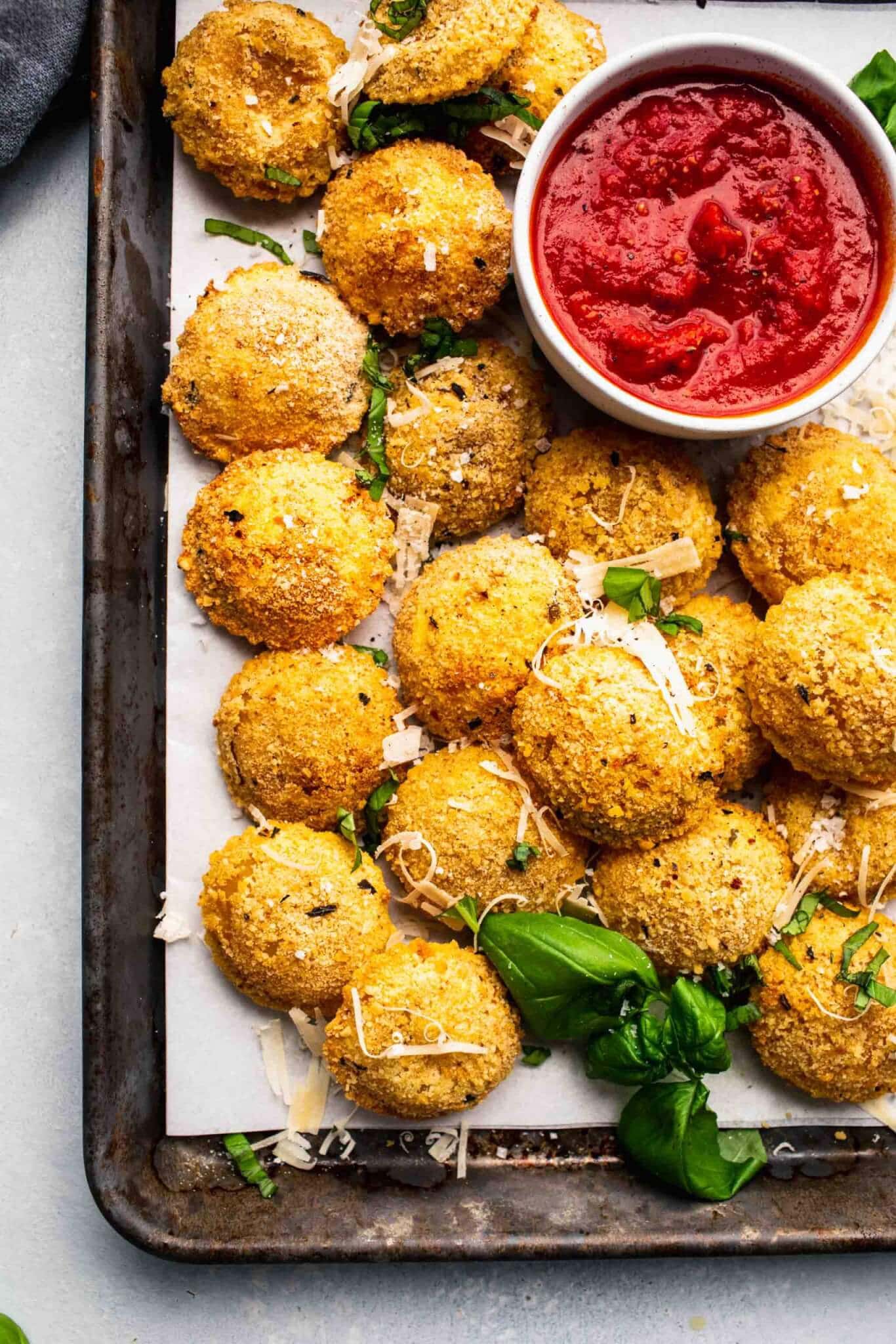 Overhead shot of serving tray of toasted ravioli with bowl of marinara sauce.