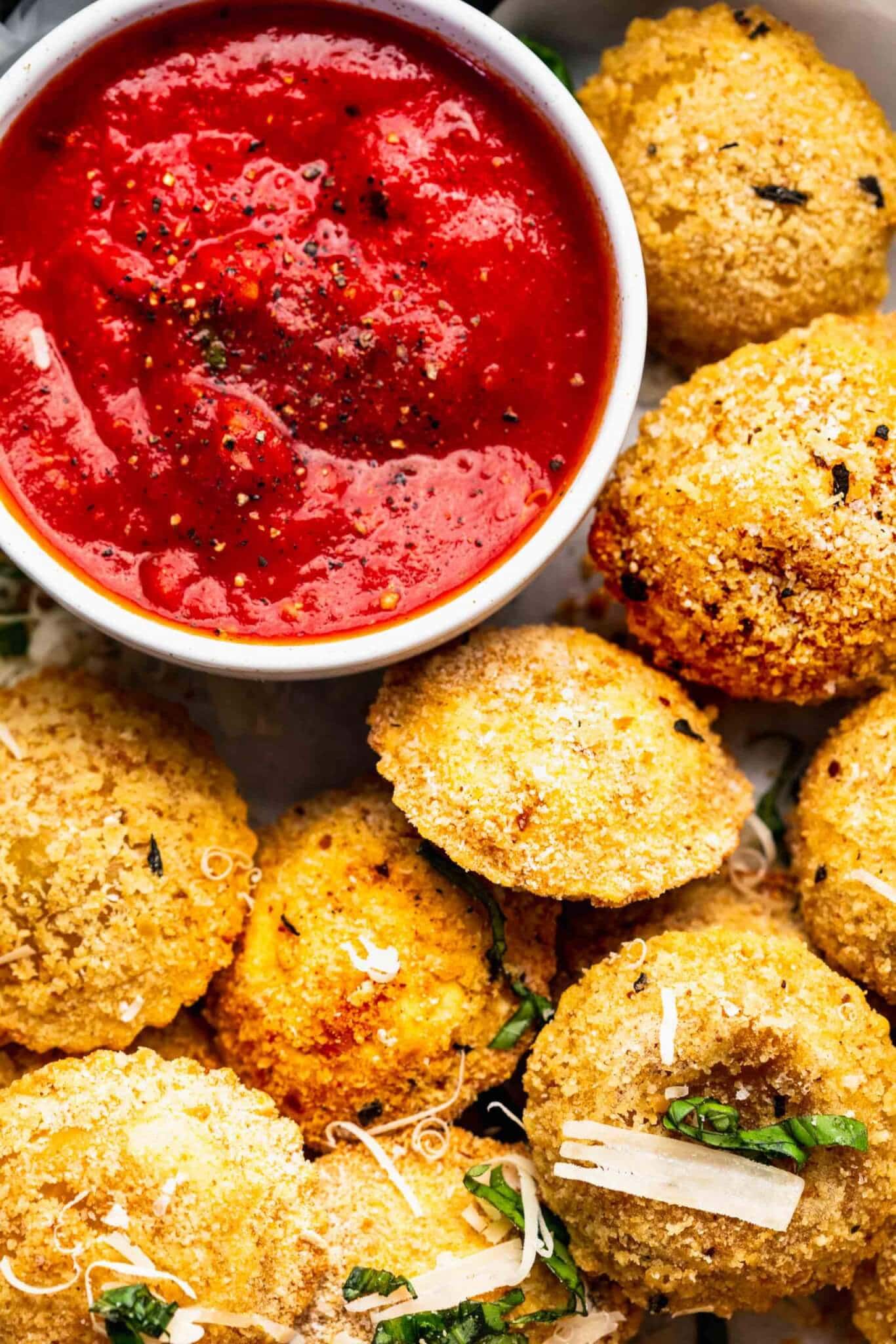 Overhead shot of serving tray of toasted ravioli with bowl of marinara sauce.