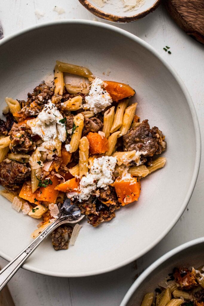 Bowl of sausage & butternut squash pasta with fork. 