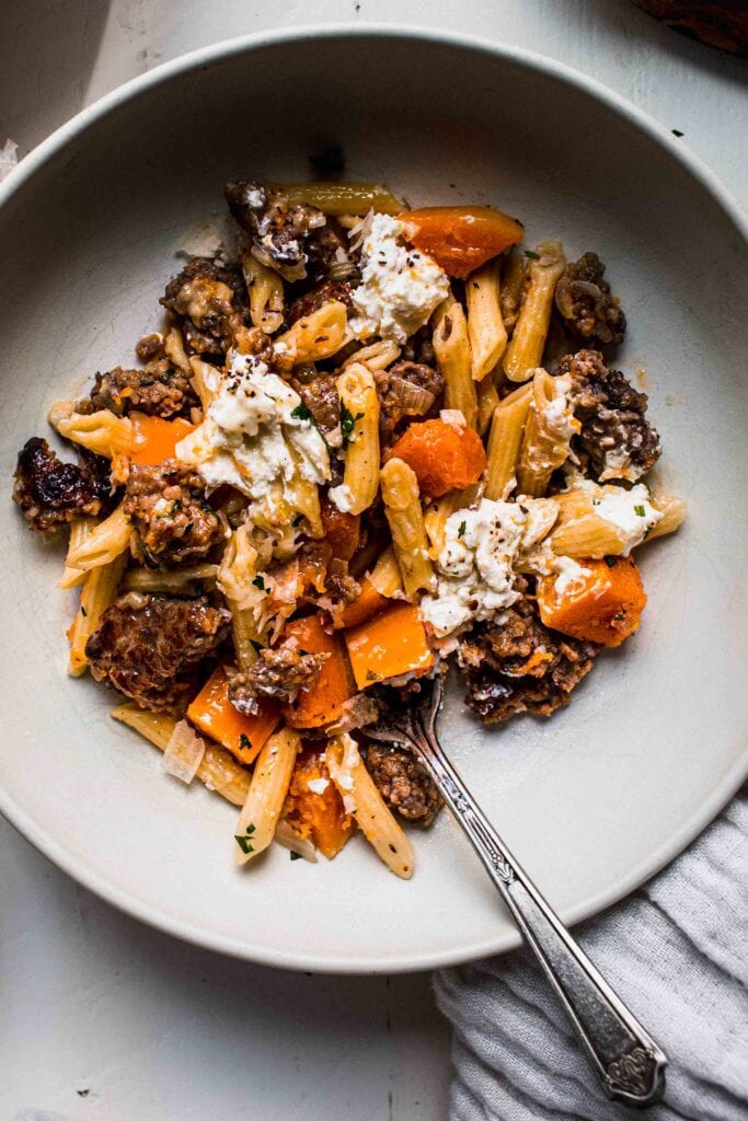 Close up of bowl of butternut pasta with fork.