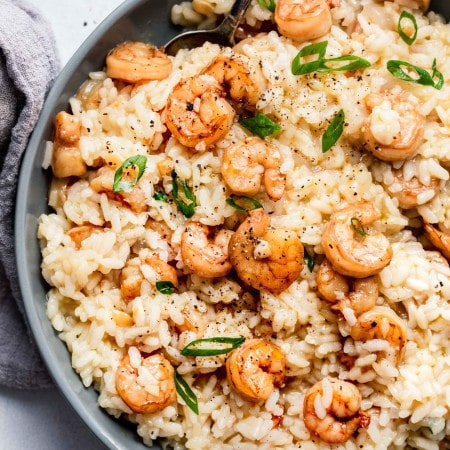 Overhead shot of prepared shrimp risotto in grey bowl with spoon.