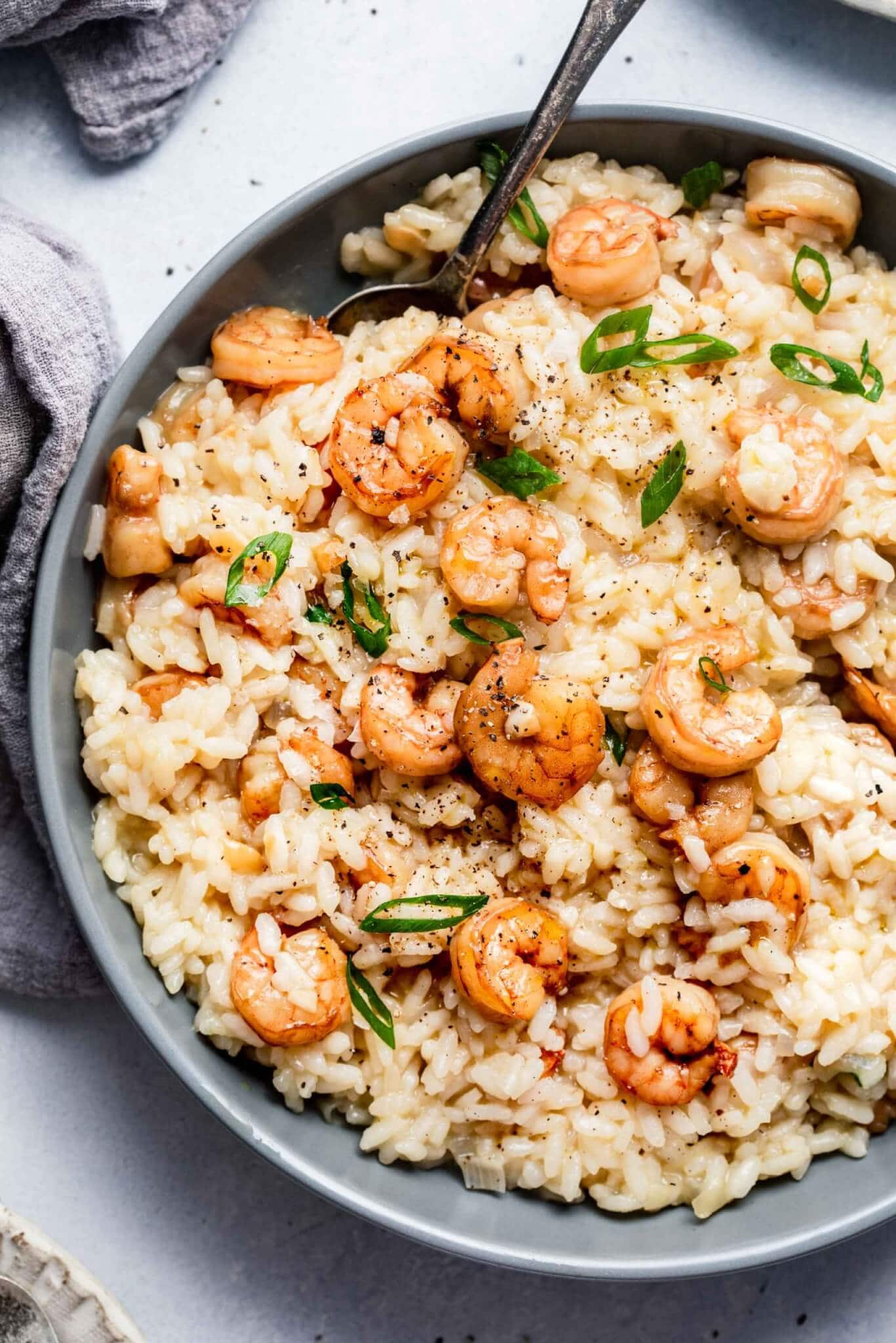 Overhead shot of prepared shrimp risotto in grey bowl with spoon.