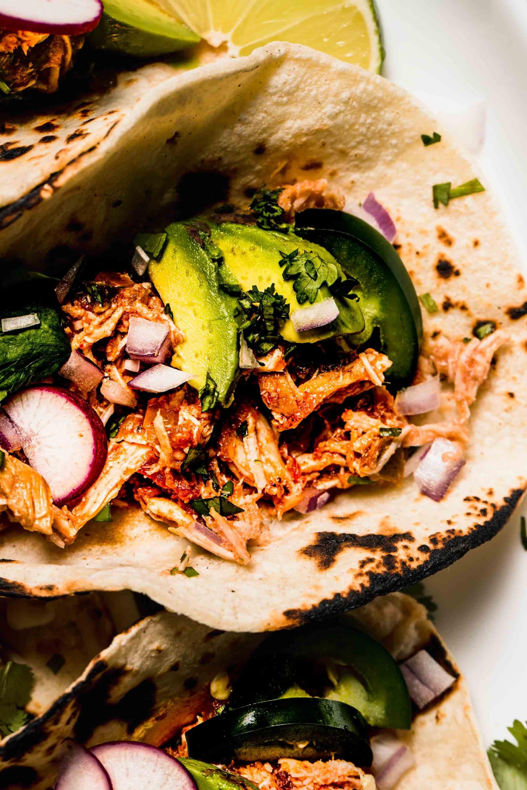 Salsa chicken piled into tortilla topped with avocado and cilantro.