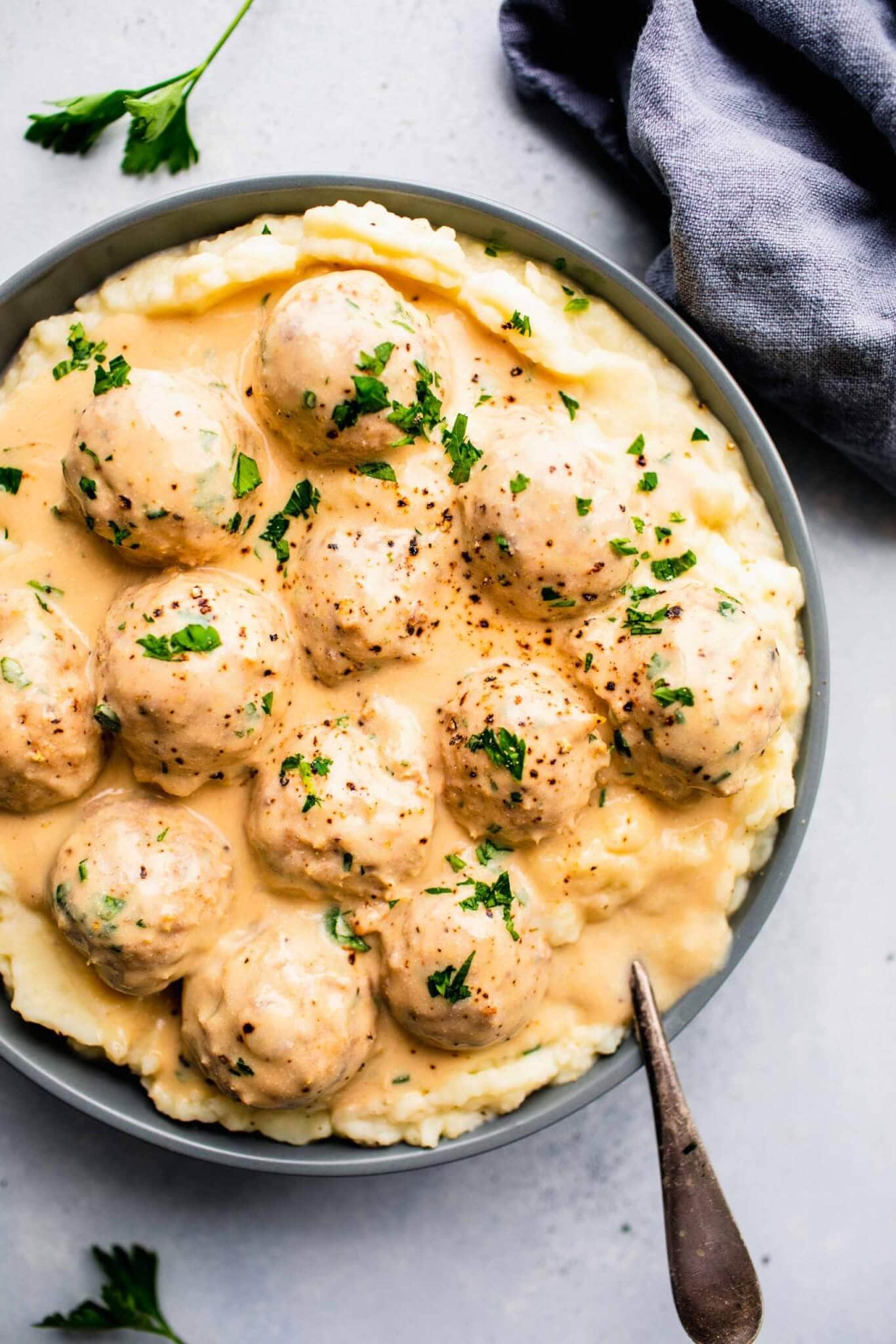 Overhead shot of bowl of turkey swedish meatballs served on top of mashed potatoes.