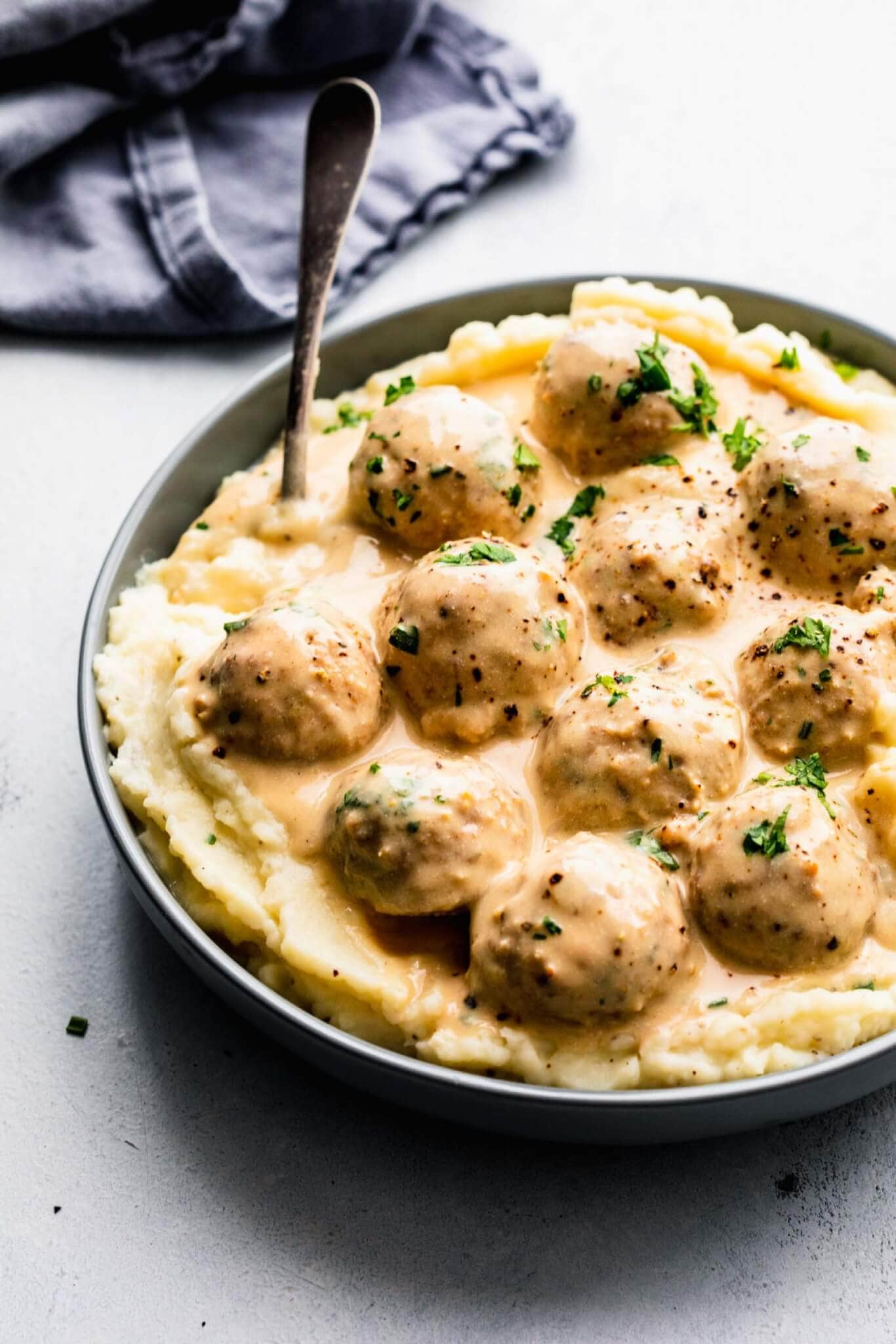 Side view of bowl of turkey swedish meatballs served on top of mashed potatoes.