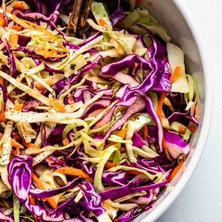Overhead close up of combined vinegar slaw in large white mixing bowl.