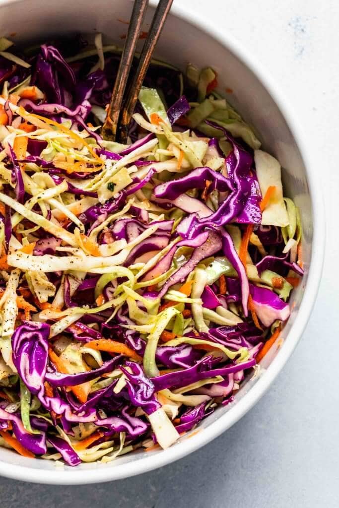 Overhead close up of combined vinegar slaw in large white mixing bowl.