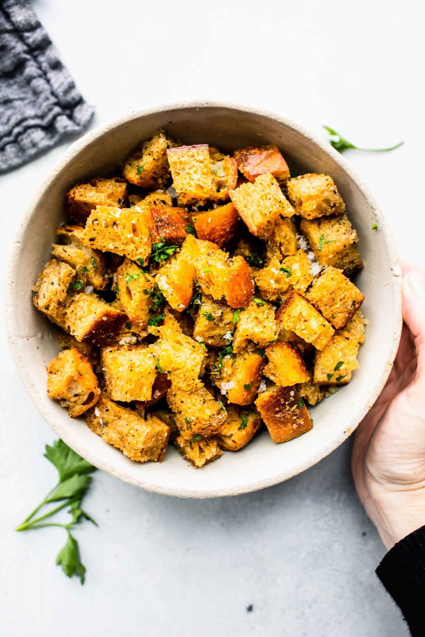 Hand holidng Bowl of croutons sprinkled with parsley. Bowl of croutons sprinkled with parsley.