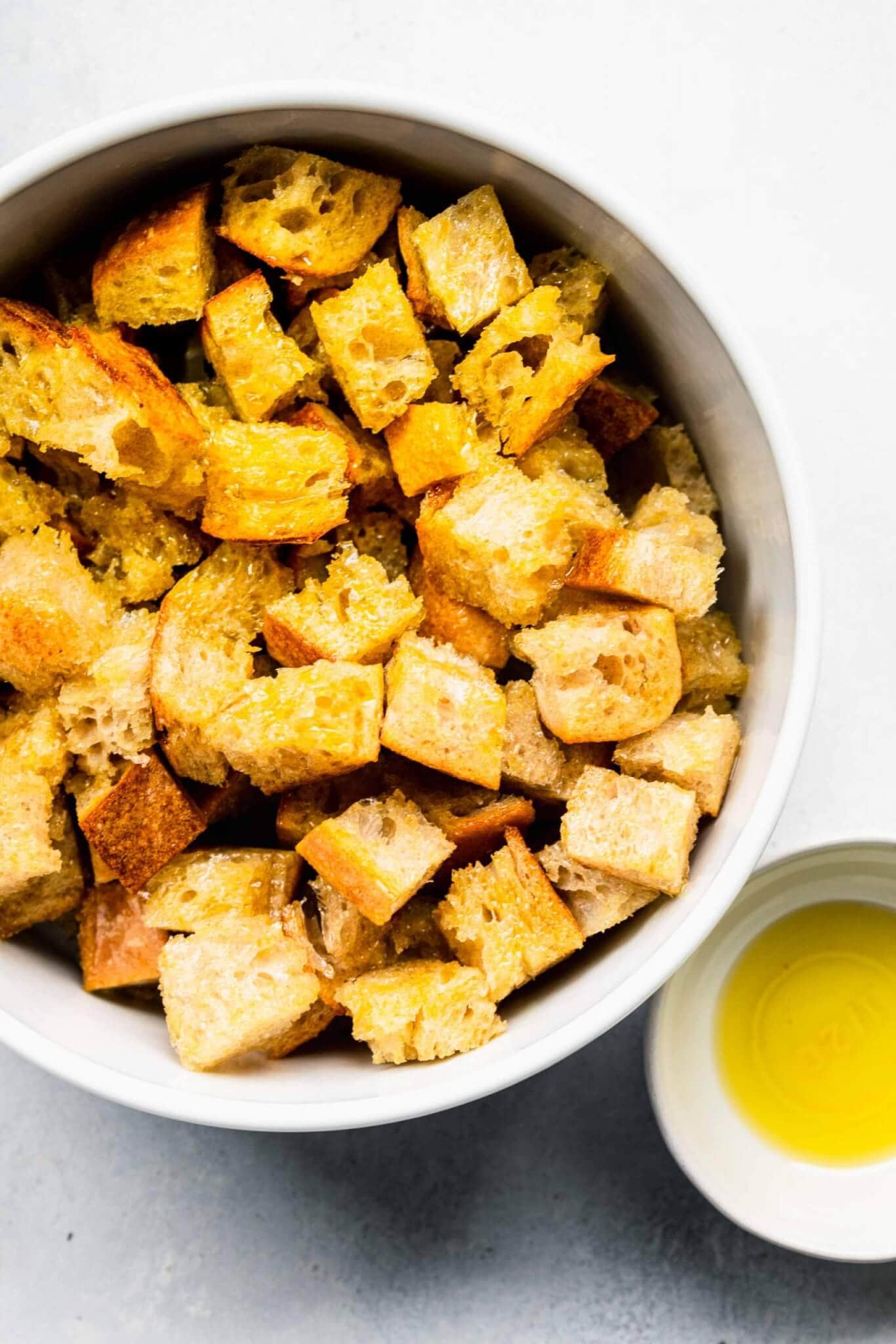 Bowl of cubes of bread tossed with olive oil.