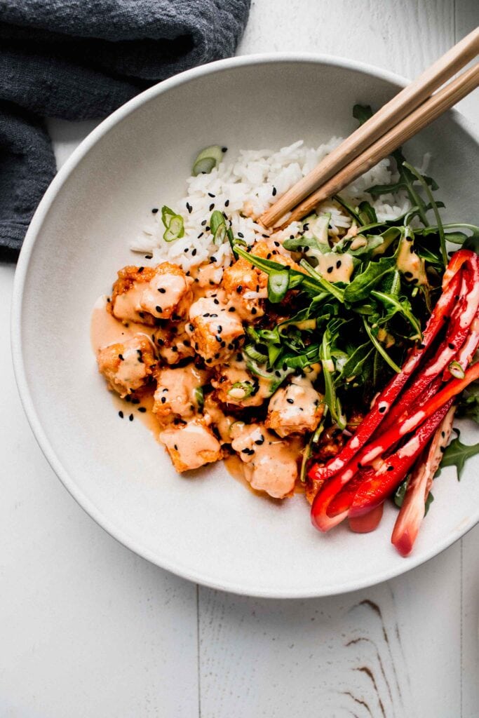 Peanut tofu arranged in white bowl with pickled peppers. 