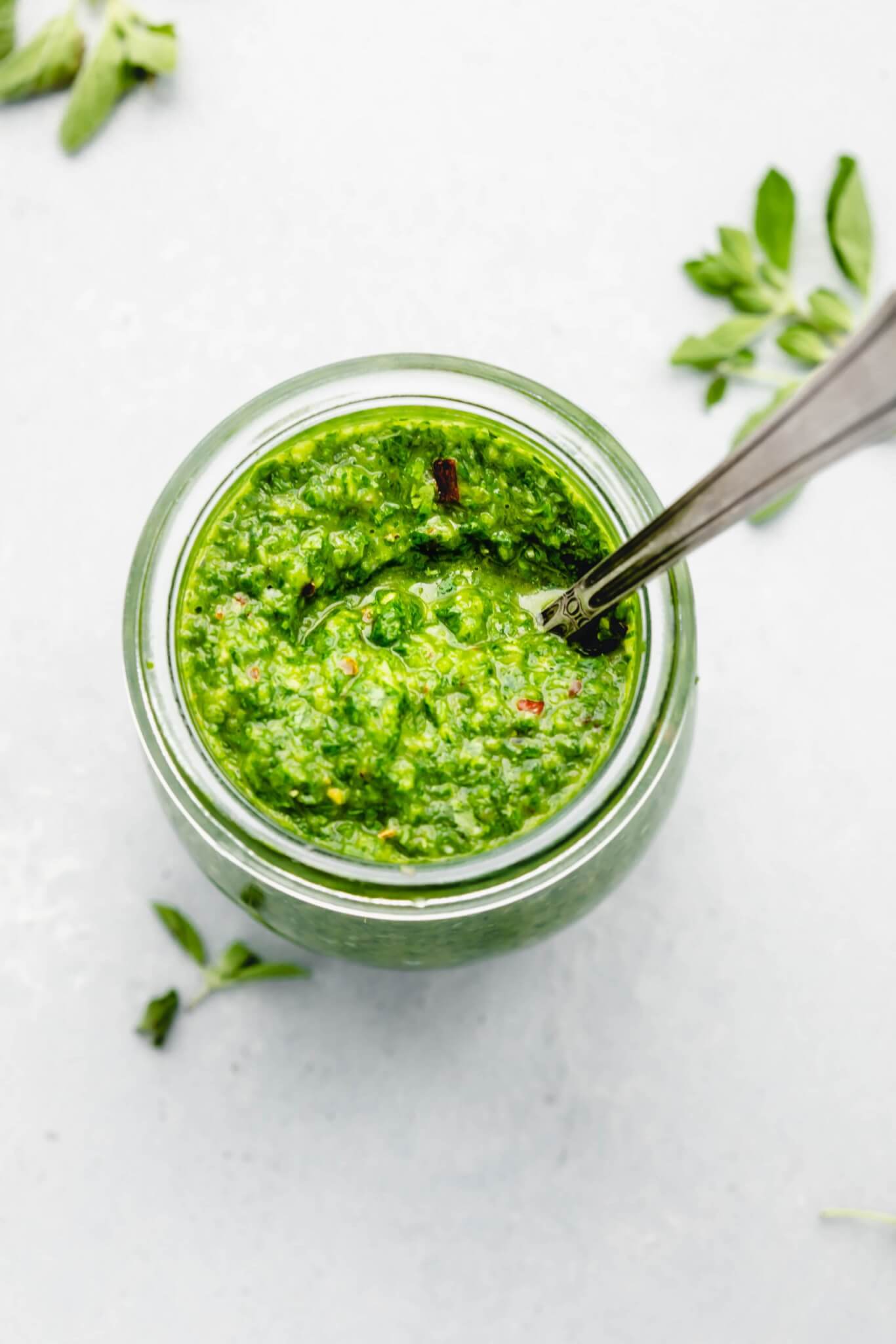 Chimichurri sauce in small jar with spoon.