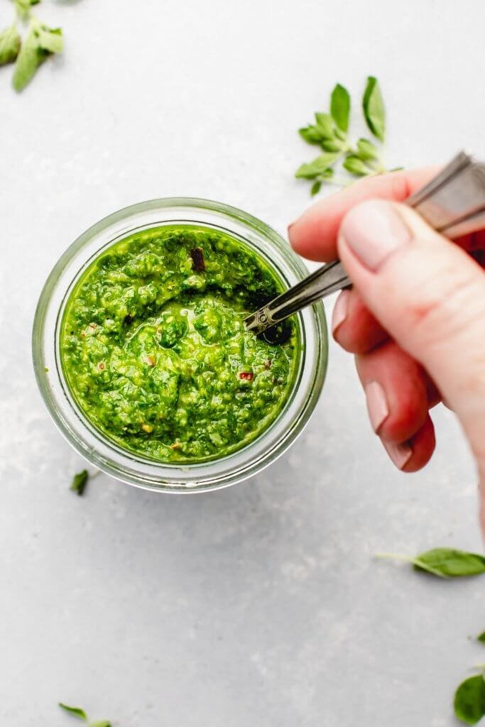 Chimichurri sauce in small jar with spoon.