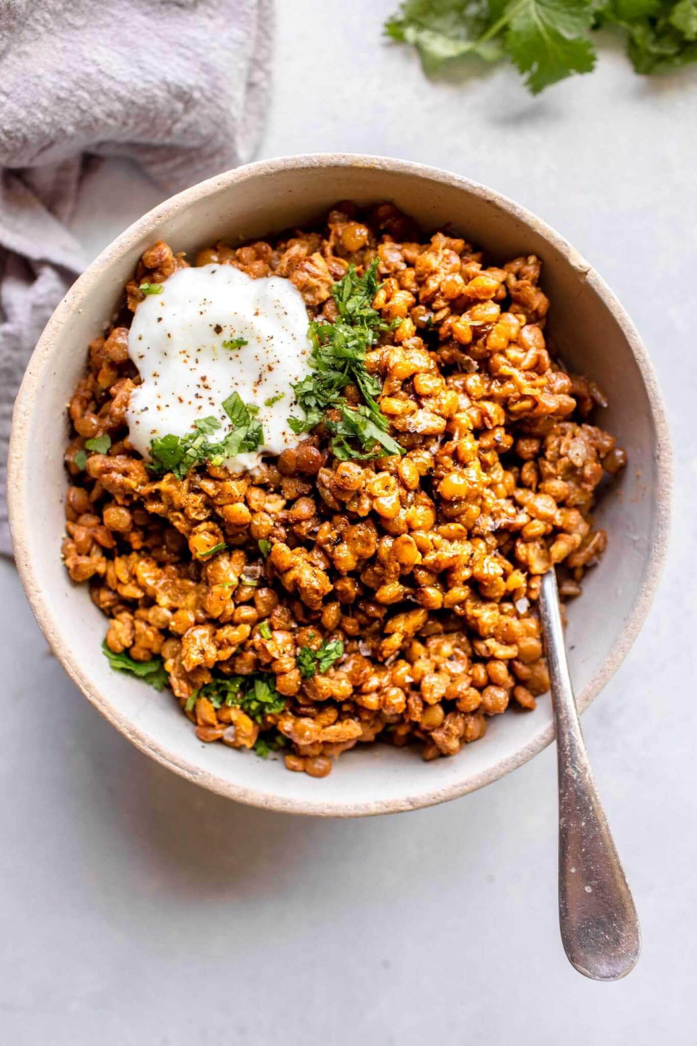 Instant pot lentils in bowl topped with yogurt and cilantro
