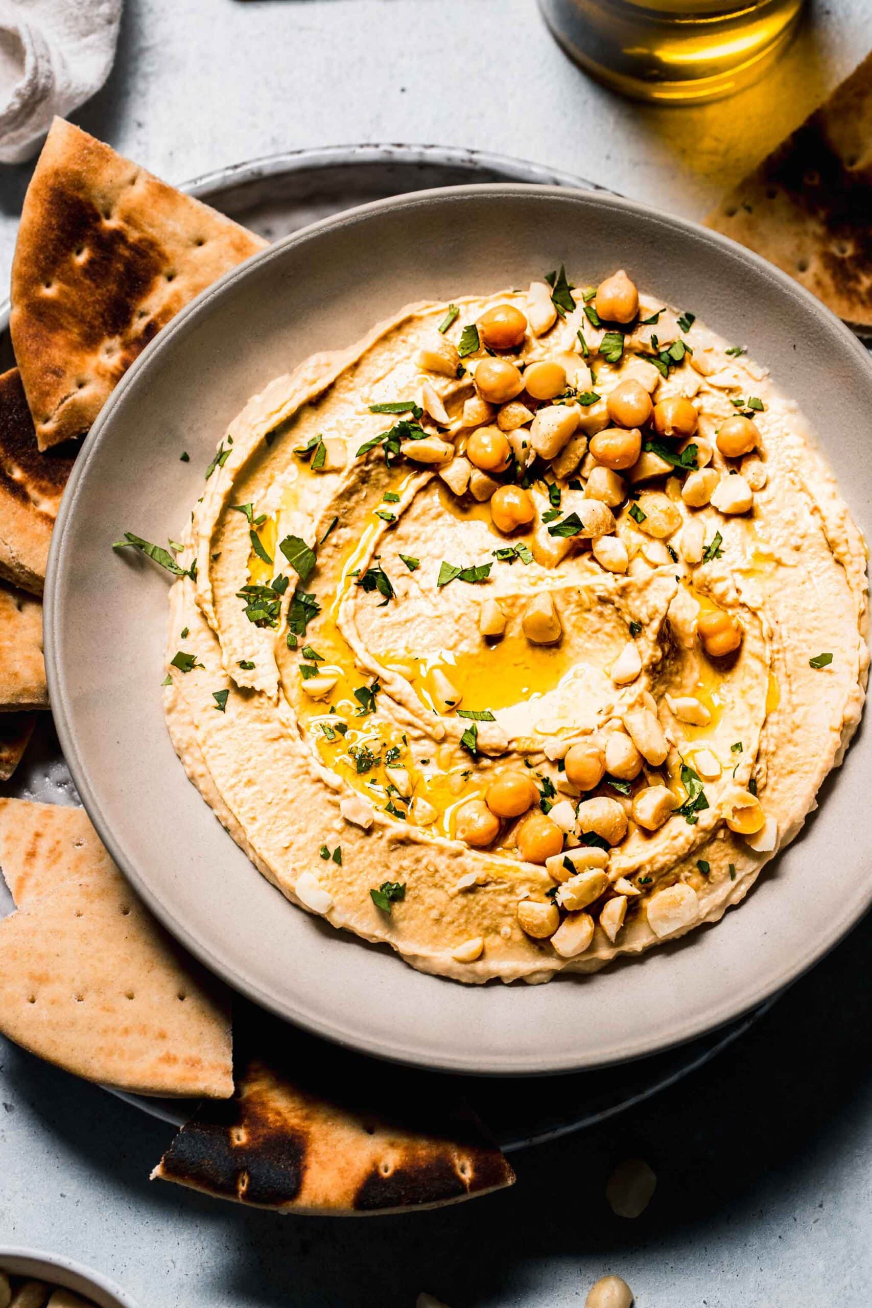 Macadamia nut hummus in bowl topped with macadamia nuts and parsley.