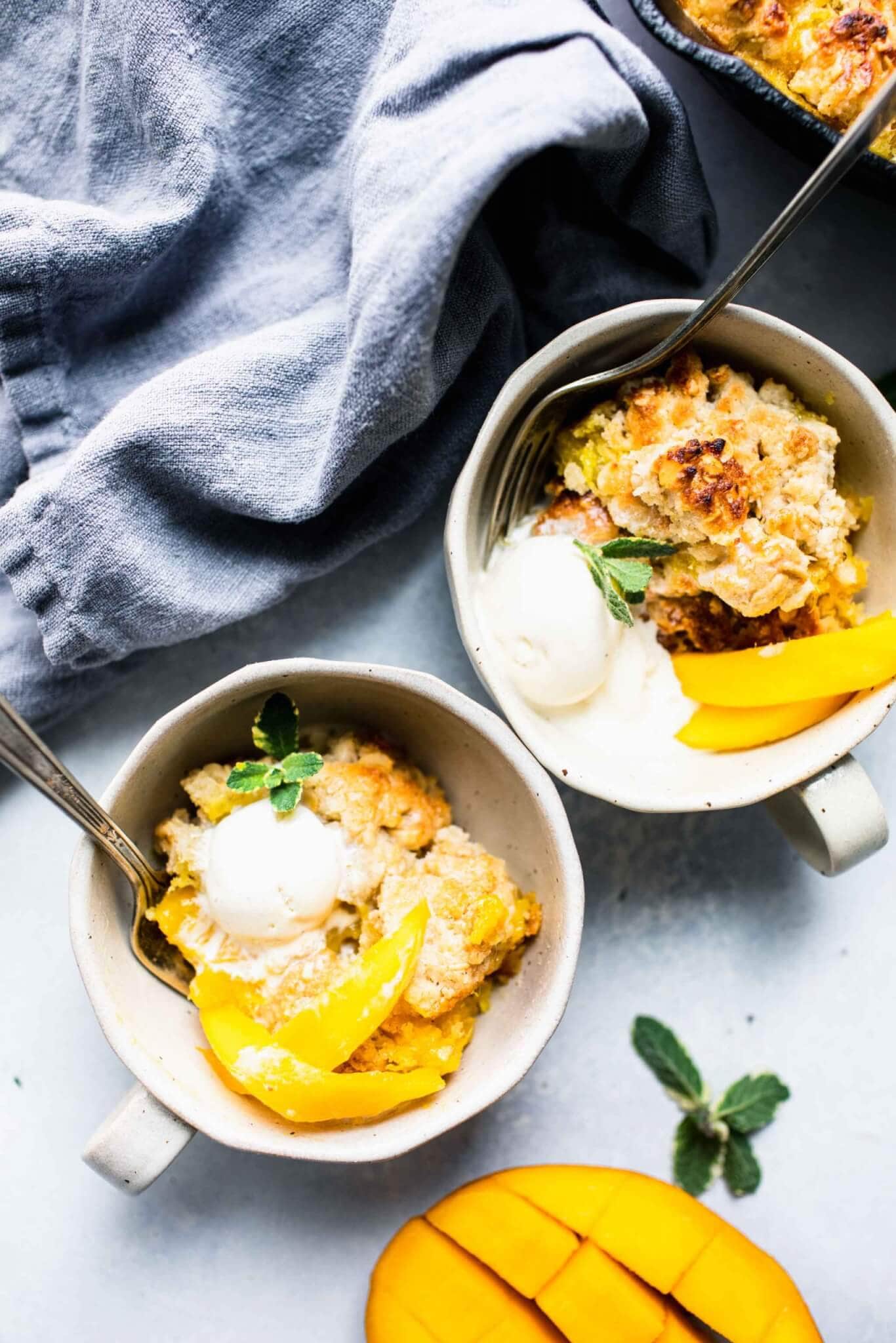 Two bowls of mango cobbler topped with ice cream.