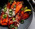 Roasted carrots in grey bowl topped with jalapenos and cotija cheese.