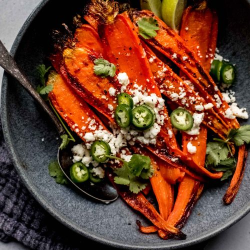 Roasted carrots in bowl with spoon.