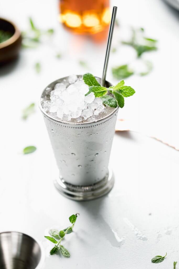 Side view of one mint julep in julep cup with sprig of mint