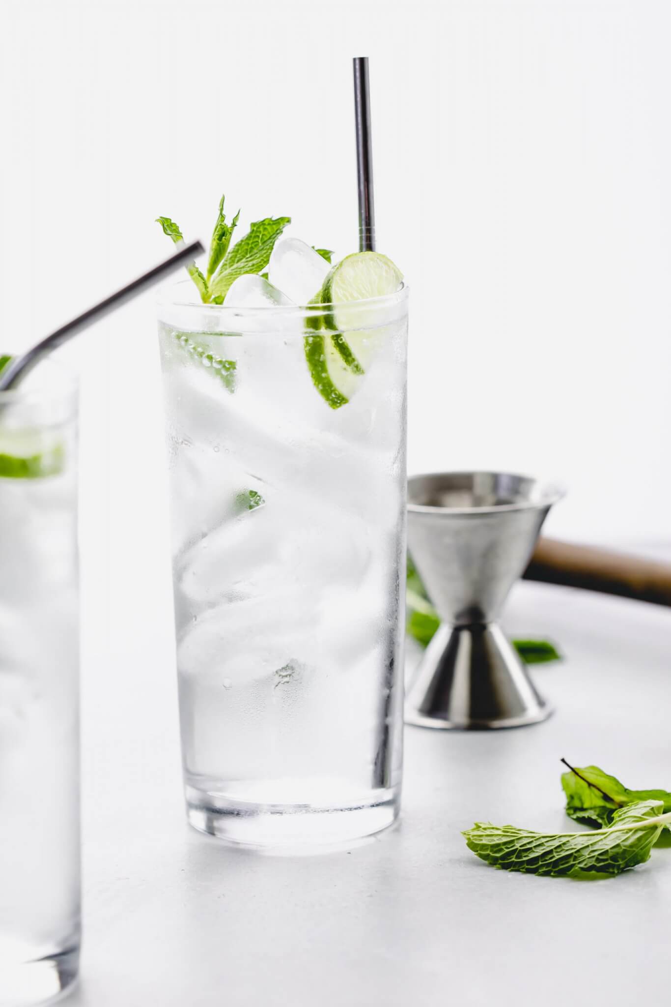 Side view of mojito garnished with limes and mint sprig.