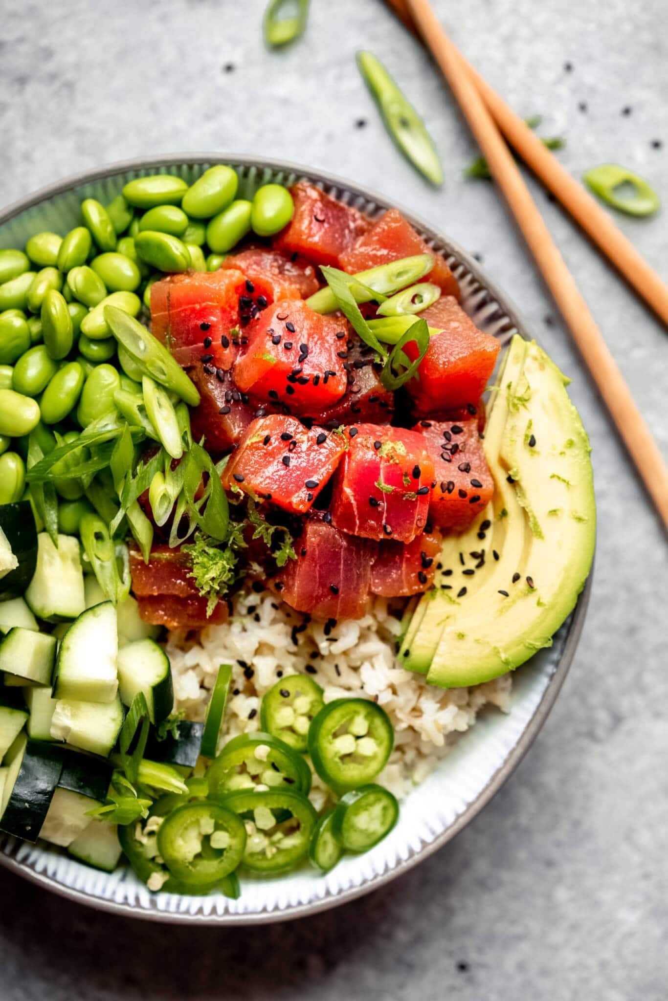 Assembled poke bowl topped with avocado, edamame, jalapeno and cucumbers.
