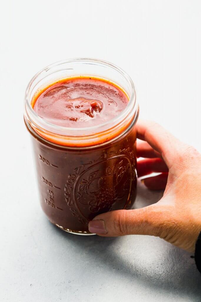 Hand holding jar of homemade bbq sauce