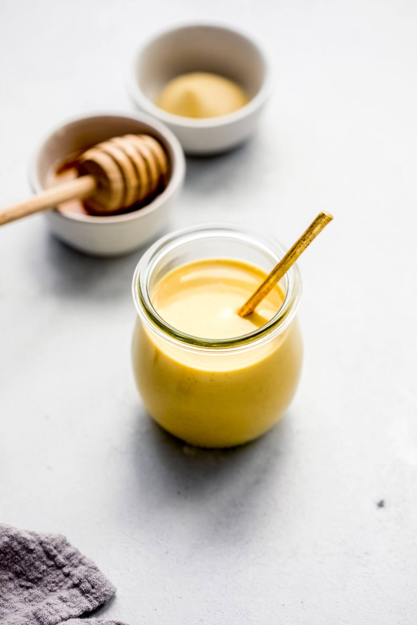Side view of  honey mustard in glass jar with gold spoon