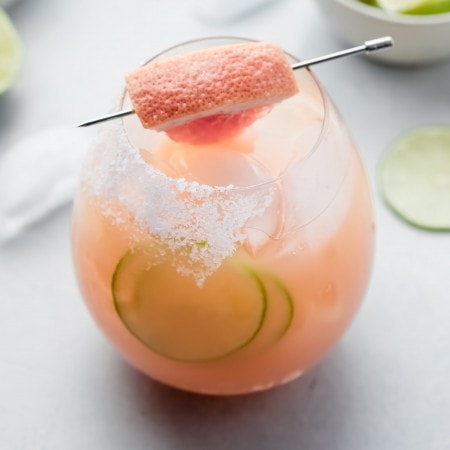 Side view of paloma cocktail garnished with grapefruit wedge.