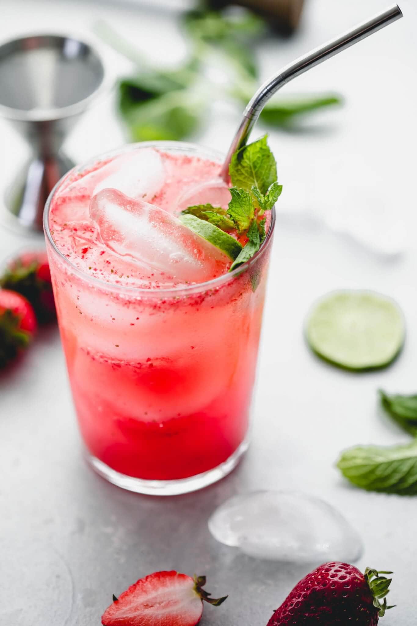 Side view of prepared strawberry mojito garnished with mint sprig and lime slices