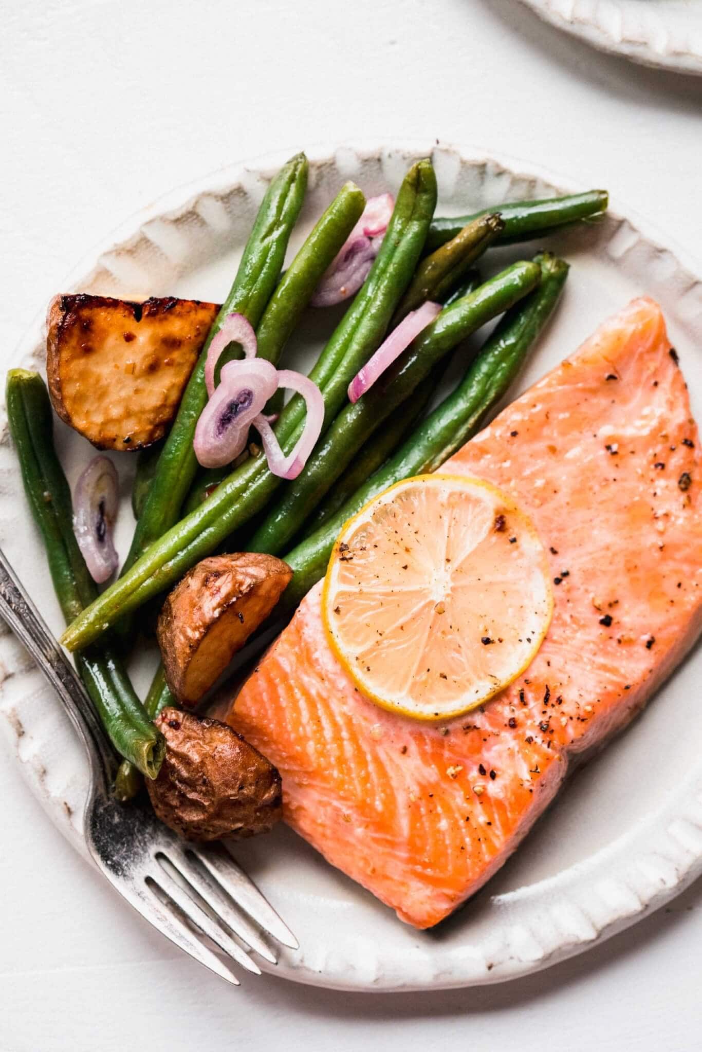 Filet of baked salmon on plate with veggies. 