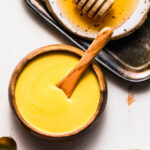 Honey mustard dipping sauce in small serving bowl next to honey wand.