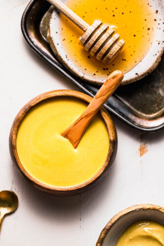 Honey mustard dipping sauce in small serving bowl next to honey wand.