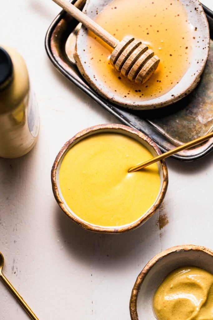 Small serving bowl of honey mustard with golden spoon.