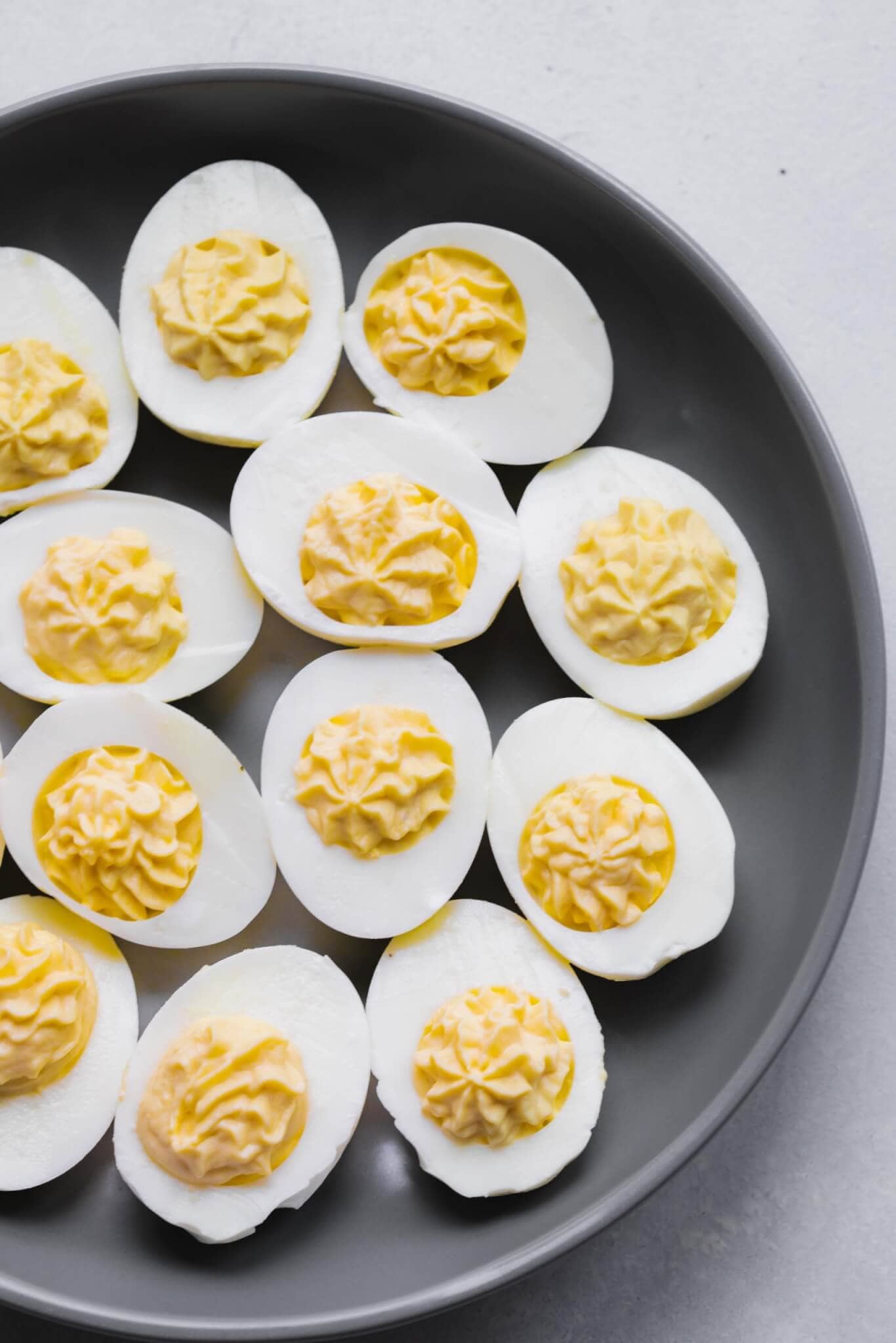 Deviled eggs on grey plate before garnishing.