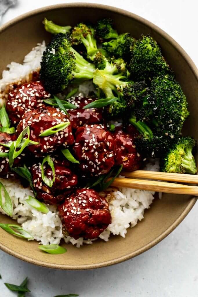 Mongolian meatballs arranged in brown bowl with rice and broccoli.