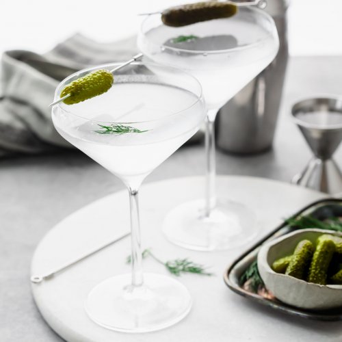 Side view of two pickle martinis in chilled glasses