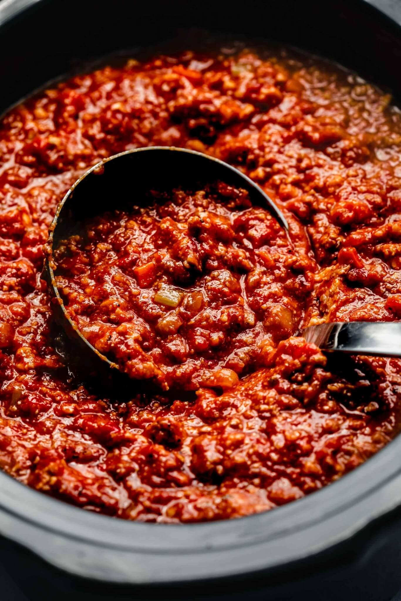 Bolognese sauce in slow cooker with ladle.