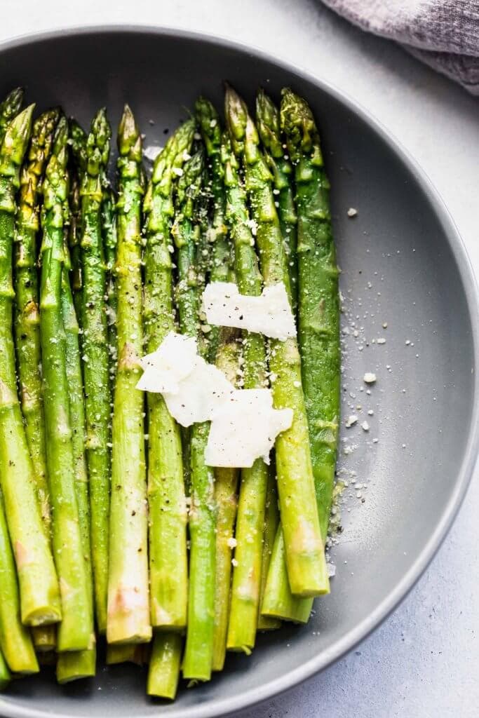 Spears of asparagus cooked sous vide topped with parmesan shavings.