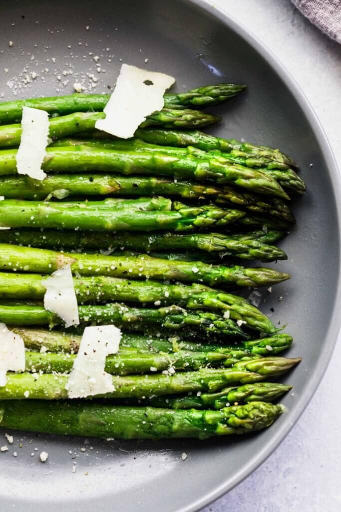 Sous vide asparagus in grey bowl topped with parmesan. 