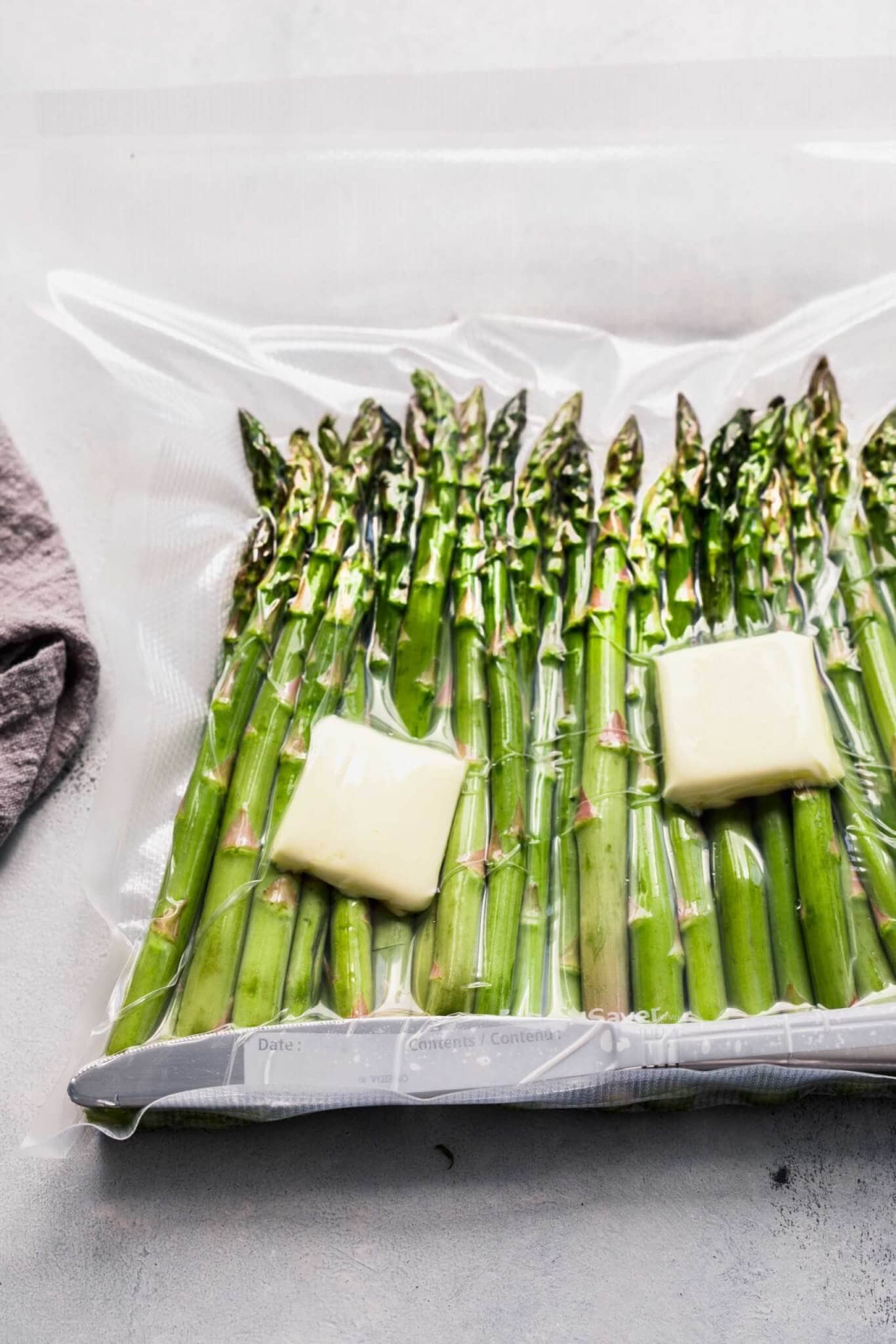 Asparagus in foodsaver bag with pats of butter before cooking sous vide.