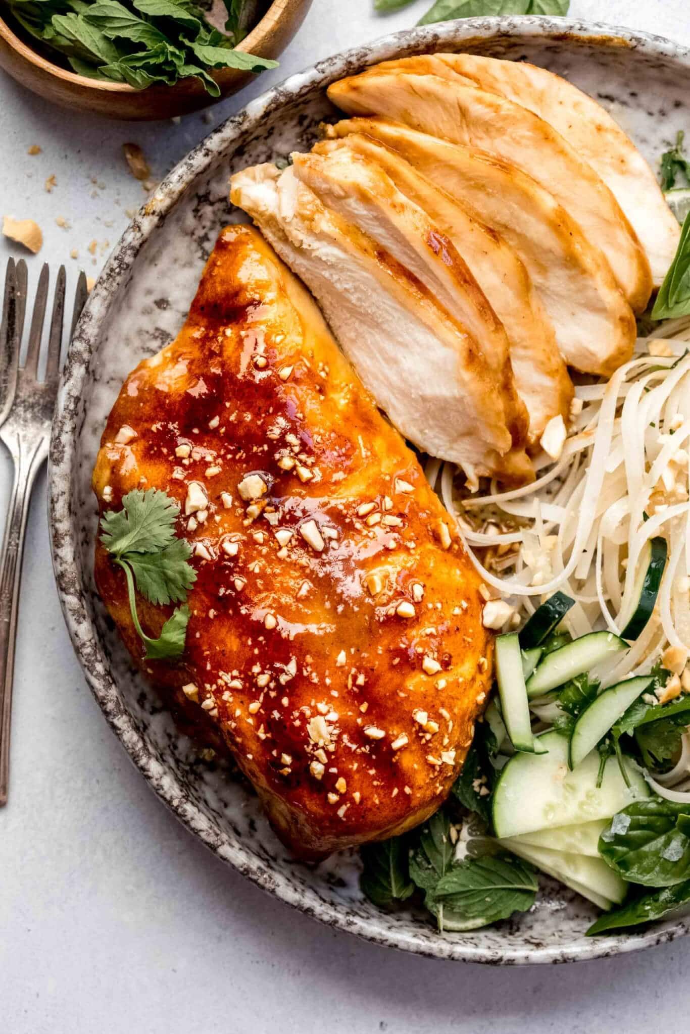 Whole sous vide miso chicken breast and sliced up miso chicken on plate with noodle salad.