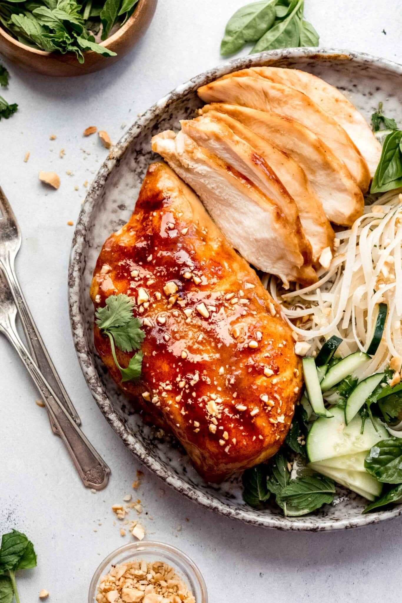 Whole sous vide miso chicken breast and sliced up miso chicken on plate with noodle salad.