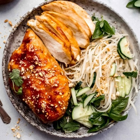 Whole sous vide miso chicken breast and sliced up miso chicken on plate with noodle salad.