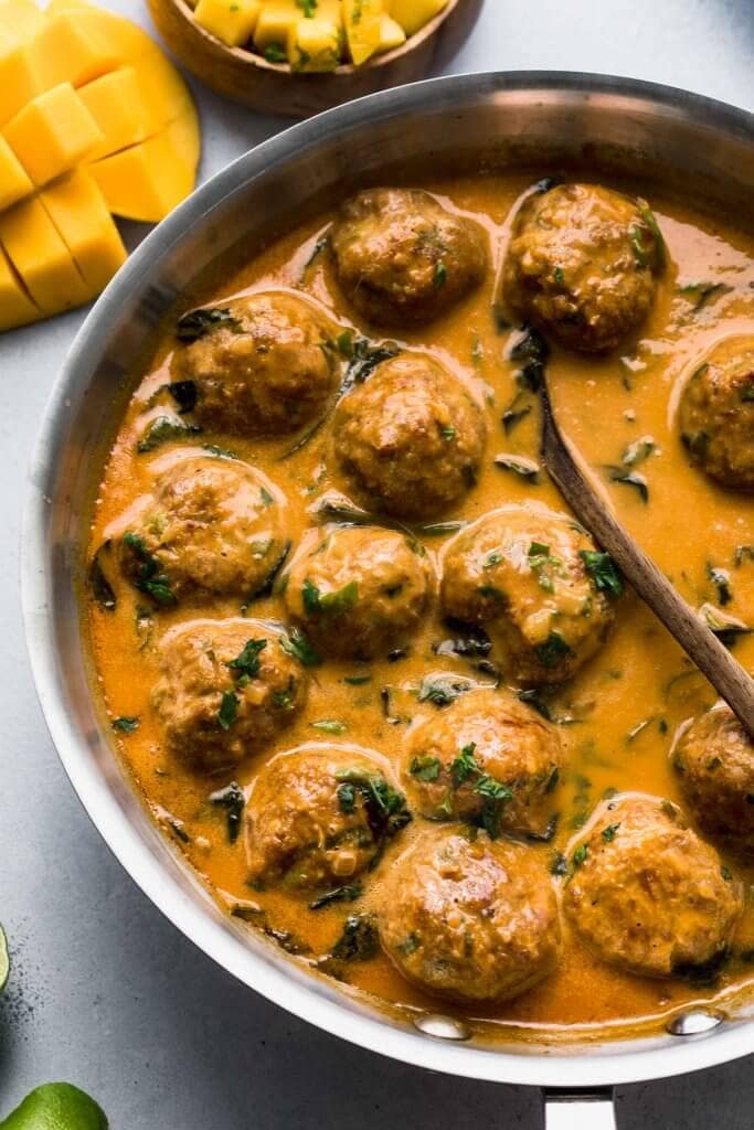 Curry meatballs simmering in skillet. 