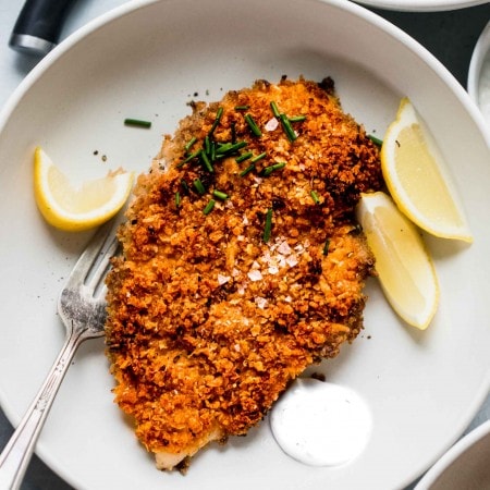 Crispy baked chicken in shallow white bowl with dollop of sour cream.