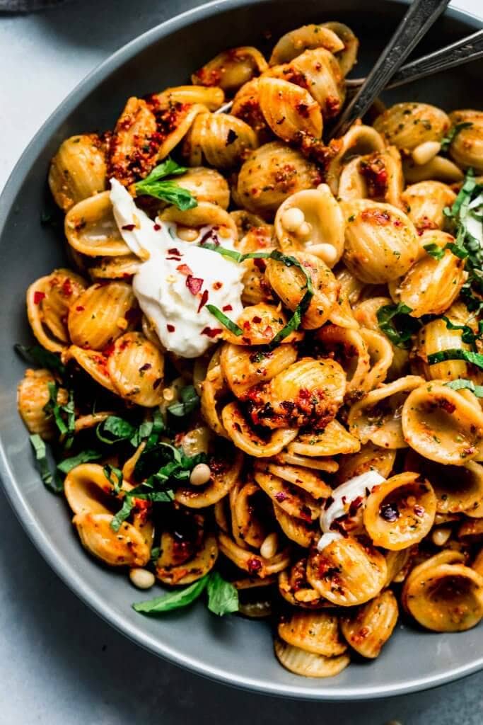 Close up of sun dried tomato pesto tossed with pasta and topped with burrata cheese.