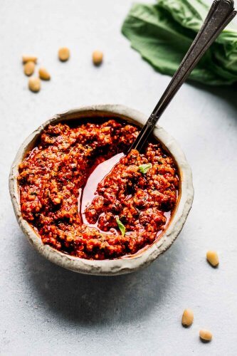 Pesto Rosso in small white bowl with spoon.