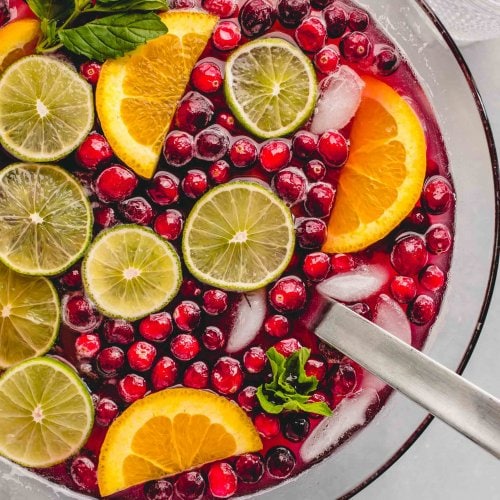 Christmas punch in bowl garnished with lime & orange slices, cranberries & mint sprigs.
