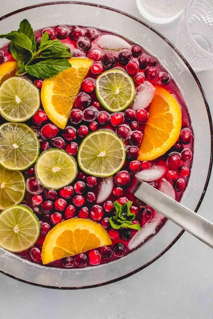 Christmas punch in bowl garnished with lime & orange slices, cranberries & mint sprigs.